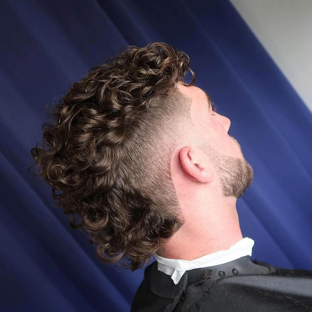 A man with a curly Mohawk fade Natural Hairstyles for Men, featuring curly hair styled into a central crest and faded sides for a modern and edgy look.