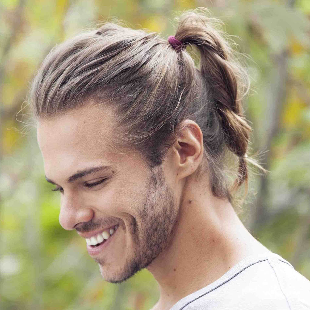 A man with a Wolf Cut for men styled into a sleek low ponytail, combining elegance with a casual twist