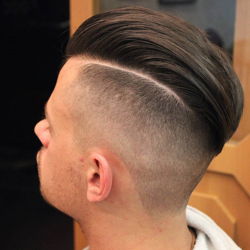 A man with a sleek hair Cut paired with an undercut, featuring a sharp contrast and modern appeal